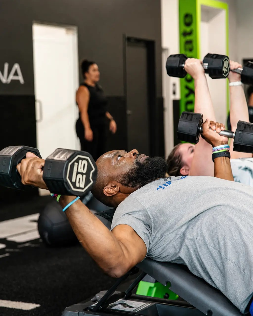Members pressing dumbbells on the benches side by side